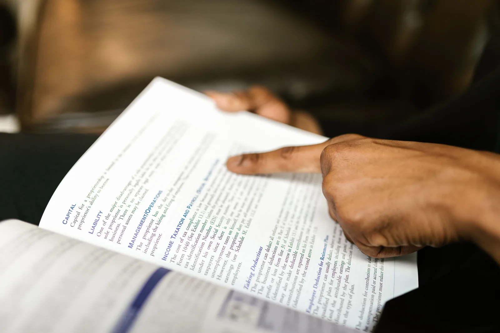 A person points to text in a book, highlighting finance content. How to read business development course outcome claims before you enroll