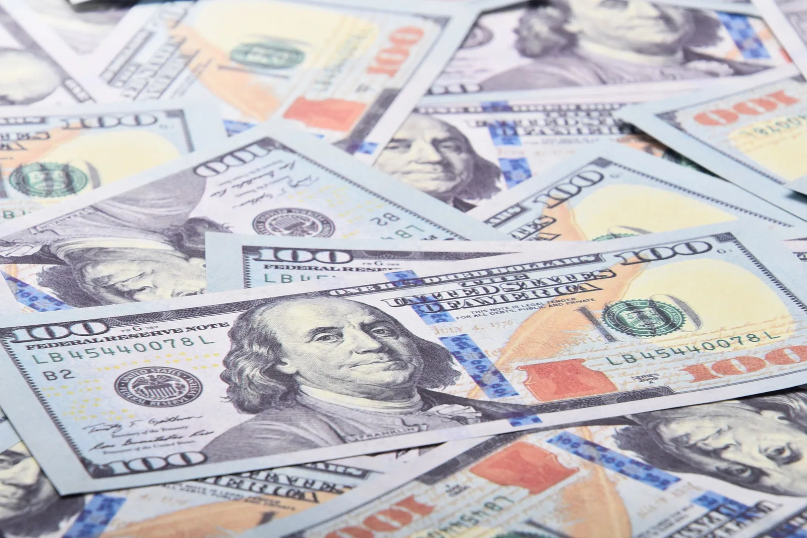 A detailed close-up of 100 US dollar bills showcasing Benjamin Franklin's portrait. How pay bands, levels and review timing shape what an employer offers