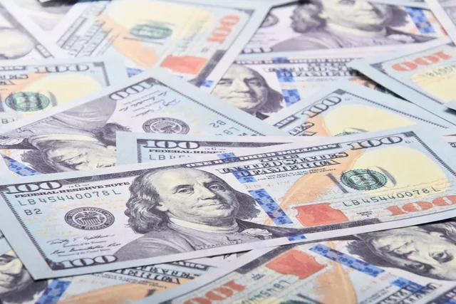 A detailed close-up of 100 US dollar bills showcasing Benjamin Franklin's portrait. How pay bands, levels and review timing shape what an employer offers