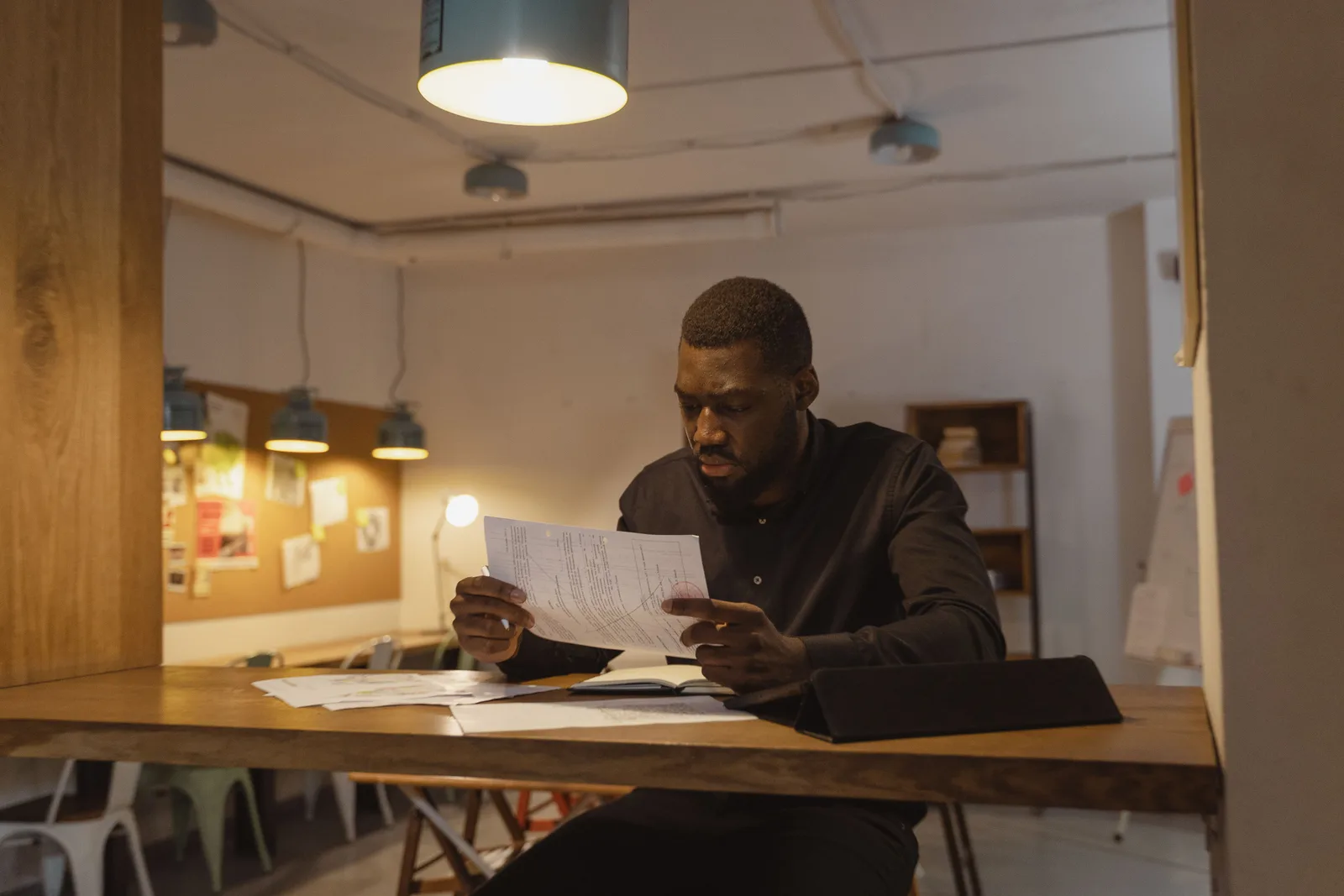 Focused man in office environment analyzing business documents at night. Resumes and cover letters employers: why they read a resume three times