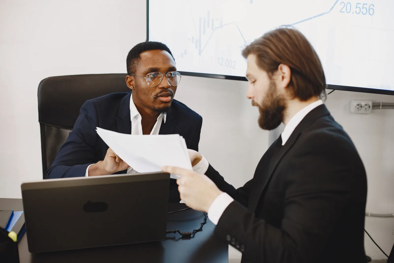 Professionals examining documents in an office business meeting setup. Pricing Validation: What a $50,000 Salary Costs an Employer