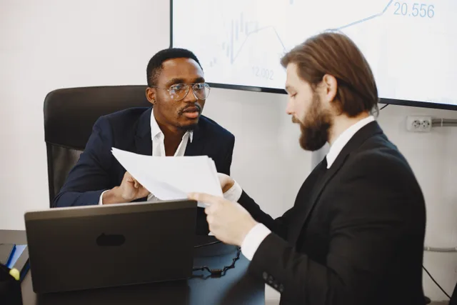 Professionals examining documents in an office business meeting setup. Pricing Validation: What a $50,000 Salary Costs an Employer